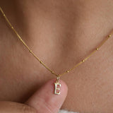 9ct solid gold initial pendant held between fingertips while worn, showing the letter charm’s size and detail.