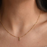 Close-up of a 9ct solid gold initial necklace against the skin, showing the small letter pendant and fine chain.