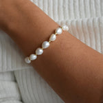 Angled view of the Aliya gold and ivory baroque pearl bracelet, showing how the pearls sit around the wrist.