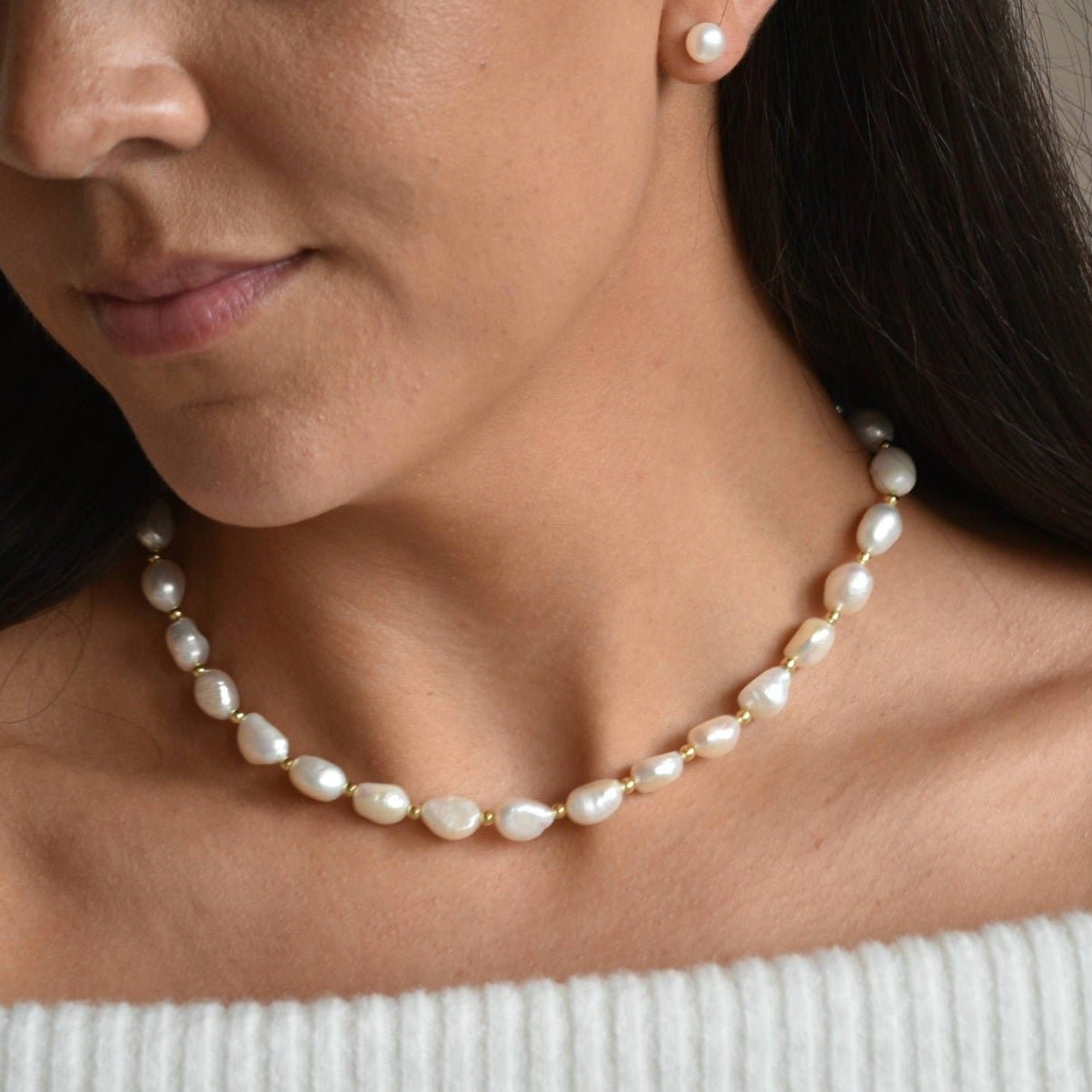 Aliya gold vermeil and ivory baroque pearl necklace worn at the collarbone, showing irregular pearls and gold details.