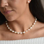Aliya gold vermeil and ivory baroque pearl necklace worn at the collarbone, showing irregular pearls and gold details.