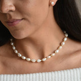 Aliya gold vermeil and ivory baroque pearl necklace worn at the collarbone, showing irregular pearls and gold details.