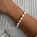 Angled view of the Aliya ivory baroque pearl bracelet with sterling silver details, showing its fit around the wrist.