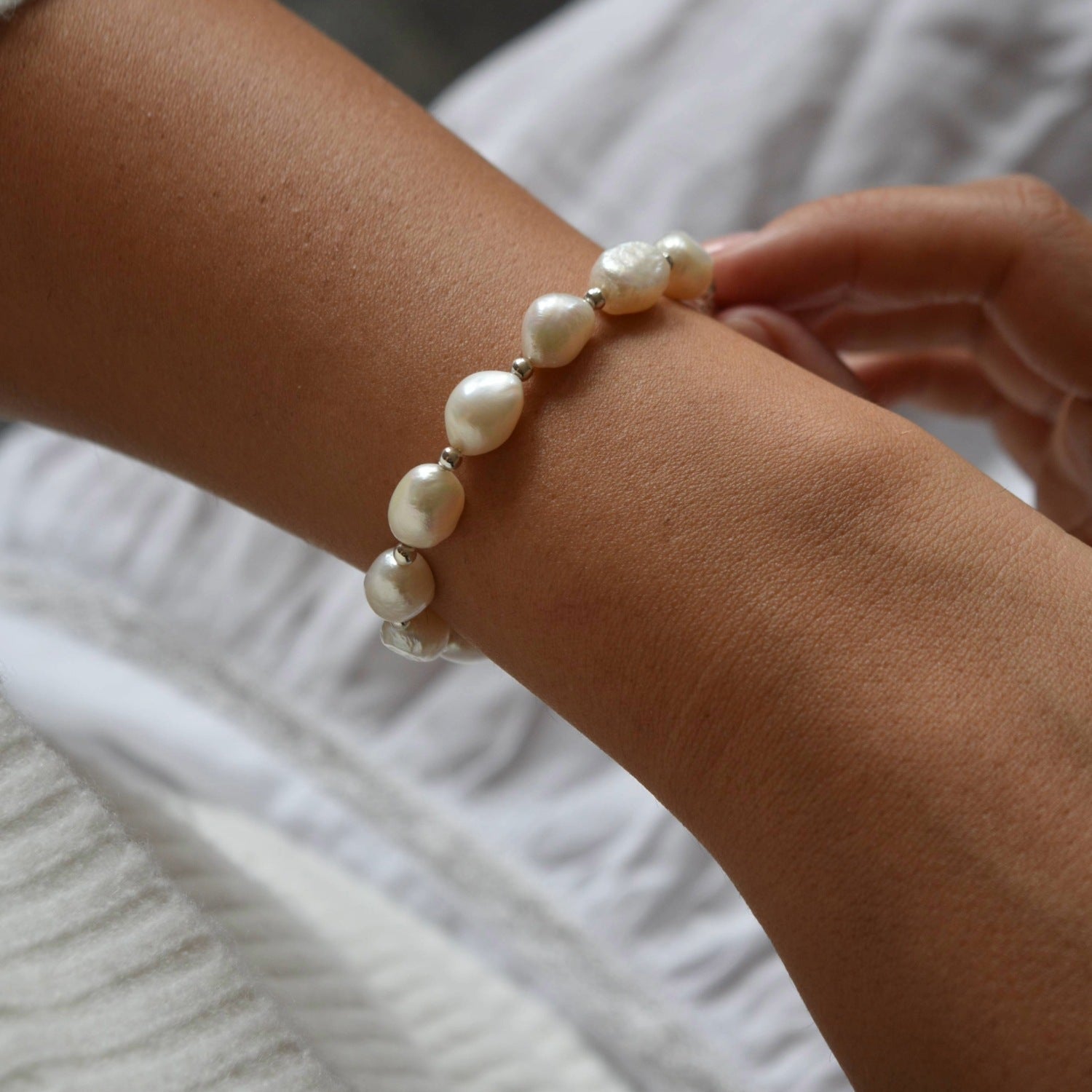 Aliya sterling silver and ivory baroque pearl bracelet worn on the wrist, with the other hand resting alongside it.