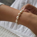 Aliya sterling silver ivory baroque pearl bracelet shown across the wrist, with the other hand touching the pearls.