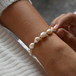 Close-up of the Aliya sterling silver bracelet, with fingertips beside the irregular ivory baroque pearls.