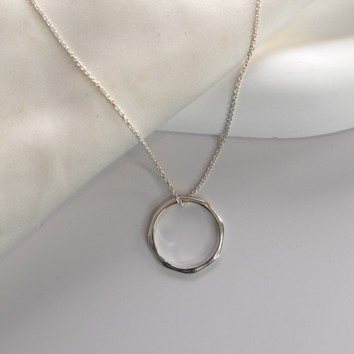 Sterling silver angled hoop pendant necklace with a modern circular pendant on a delicate chain.
