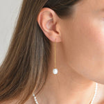 Side view of a gold vermeil ivory pearl threader earring, showing the length of the drop below the earlobe.