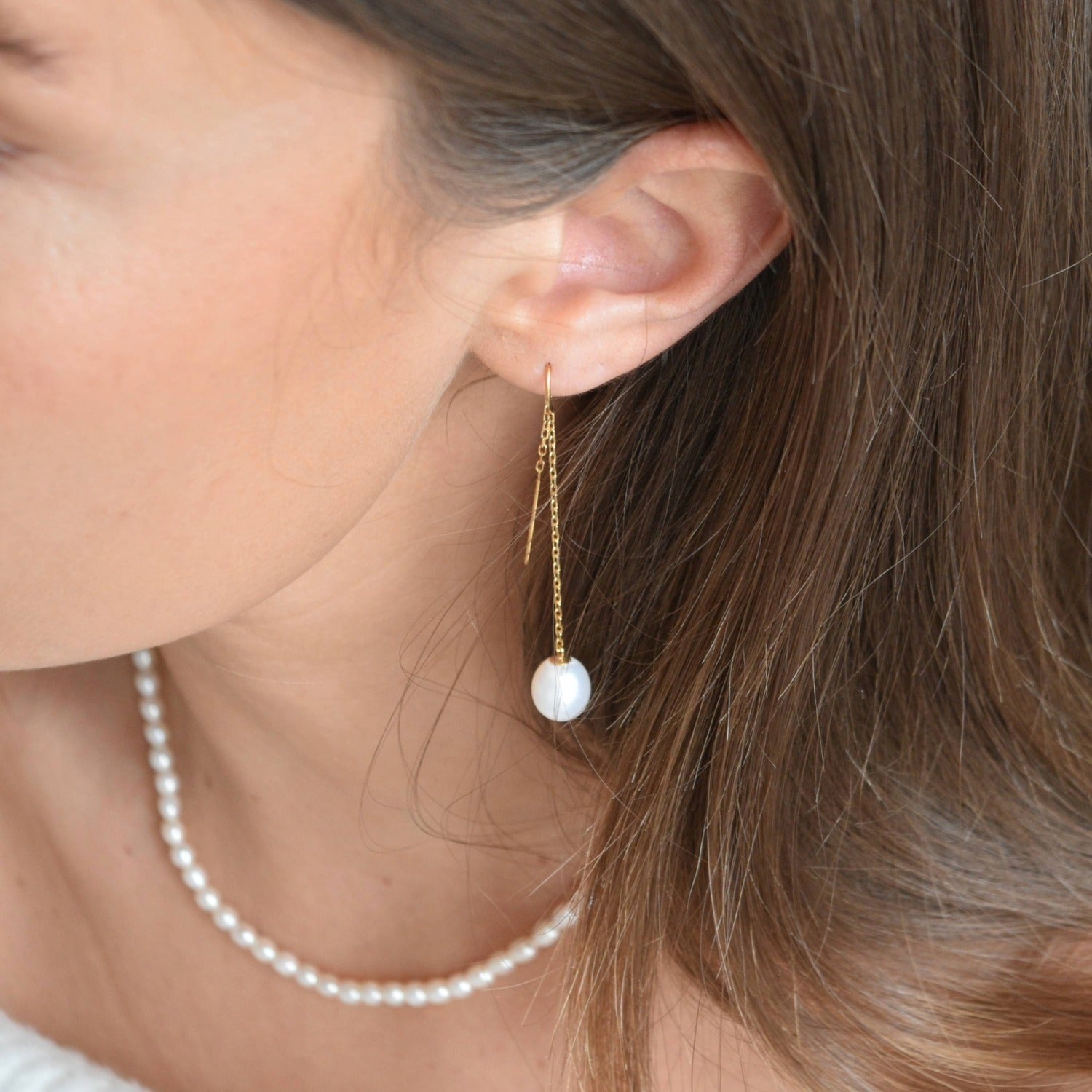 Gold vermeil pearl threader earring worn beside the neck, with an ivory pearl suspended from a fine chain.