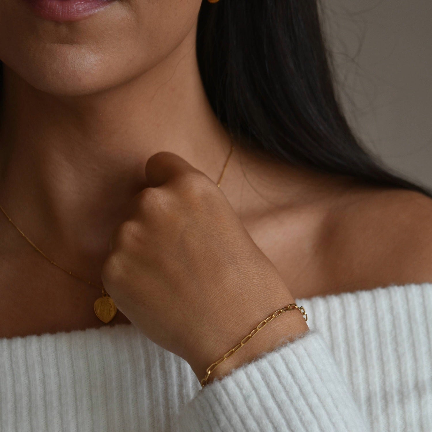 Gold vermeil paperclip chain bracelet shown on a model’s raised wrist, with her hand resting beneath her chin.