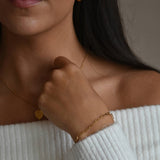 Gold vermeil paperclip chain bracelet shown on a model’s raised wrist, with her hand resting beneath her chin.
