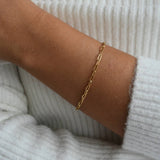 Gold vermeil paperclip chain bracelet worn on the wrist, showing its fine elongated links against the skin.