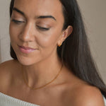 Gold vermeil paperclip chain necklace worn at the collarbone, shown on a model looking down.