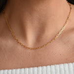 Close-up of a gold vermeil paperclip chain necklace, showing its elongated links above a pale ribbed neckline.