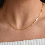 Close-up of a gold vermeil paperclip chain necklace, showing its elongated links above a pale ribbed neckline.