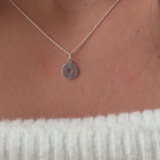 a model wearing a sterling silver compass pendant on a fine silver trace chain 