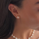 a model wearing a pearl button stud earring