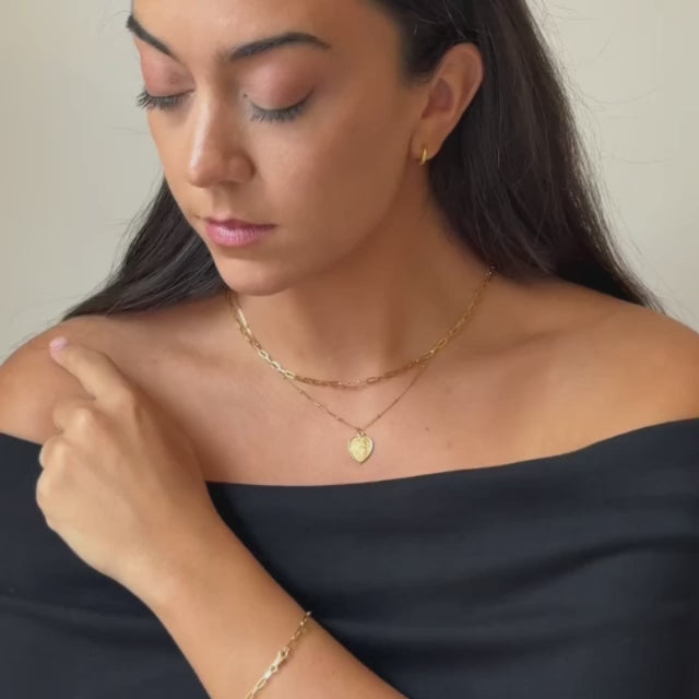 a model wearing a set of gold vermeil jewellery. A delicate gold paperclip chain link necklace, a delicate gold st Christopher pendant necklace and a gold paperclip link bracelet 