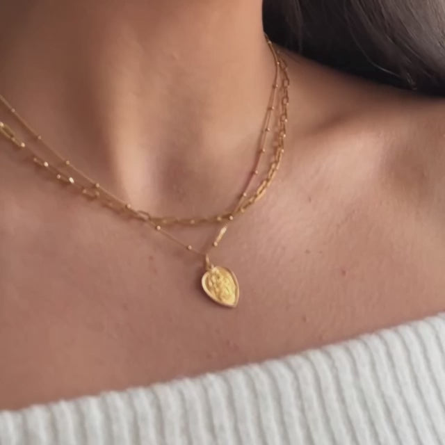 a model wearing a gold st Christopher necklace layered with a gold vermeil paperclip chain necklace 