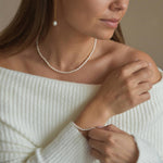 Riya ivory seed pearl bracelet with sterling silver details, worn with the wrist lifted beside the shoulder.
