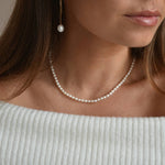 Riya sterling silver ivory seed pearl choker necklace worn at the base of the neck, shown from a slight side angle.