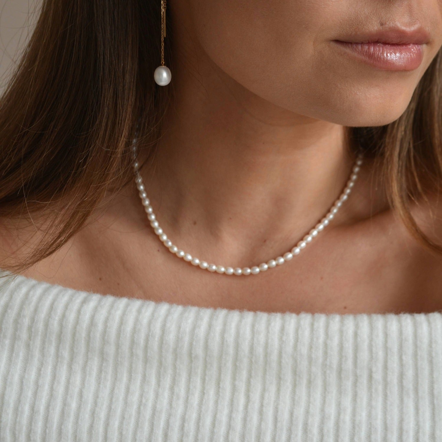 Riya sterling silver ivory seed pearl choker necklace worn at the base of the neck, shown from a slight side angle.