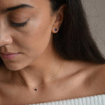 Solid 9ct gold September birthstone necklace shown on a model looking down, with the blue pendant centred at her neckline.
