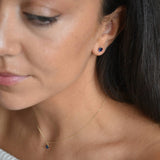 Solid 9ct gold September birthstone stud earrings shown in an angled portrait, with the model’s hair behind her ear.
