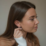 Sterling silver CZ star huggie earrings shown on a model in side profile, with her hair tucked behind her ear.