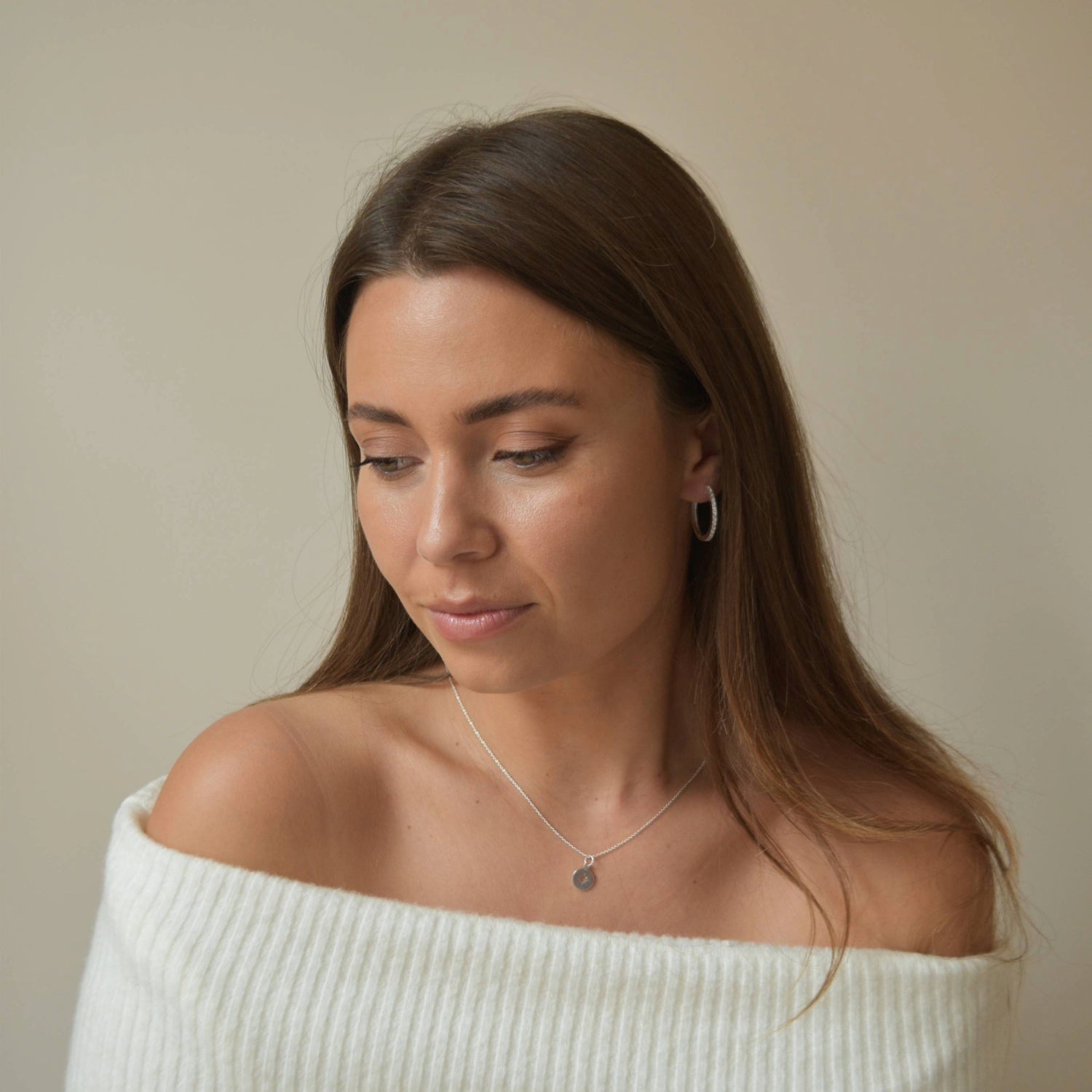 Sterling Silver Slim CZ Huggie Earrings worn on a model in a white knit top 