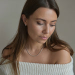 Sterling silver snake chain necklace shown on a model looking down, illustrating its length when worn.